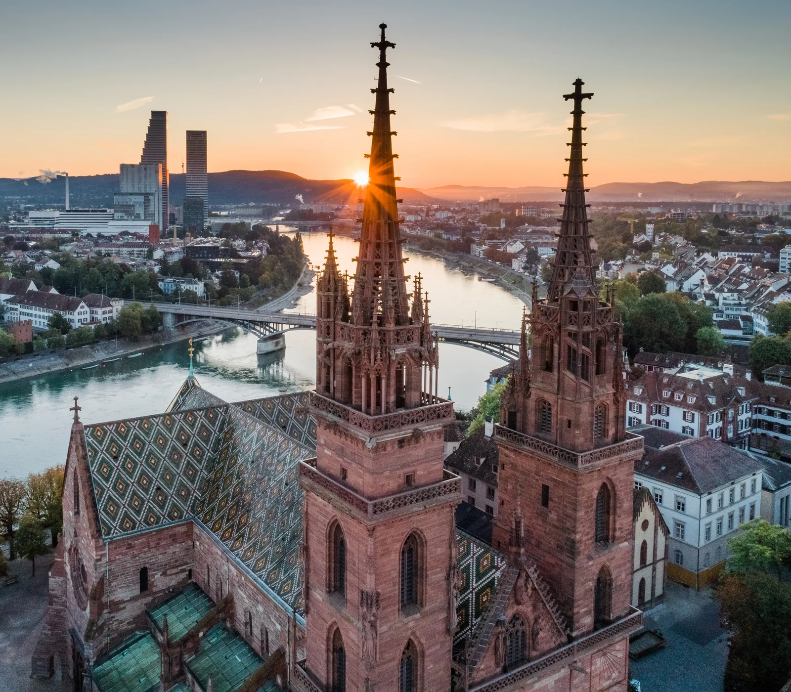 Basel Minster with both towers, its patterned roof and the Rhine at sunset