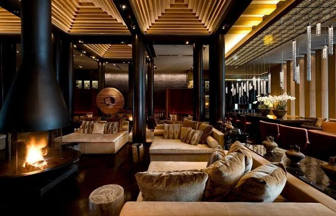 The Chedi Andermatt lounge with fireplace, seating and warm Asian-Alpine interior design