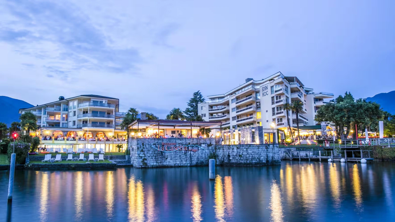 Hotel Eden Roc Ascona illuminated on the waterfront with its name visible above Lake Maggiore