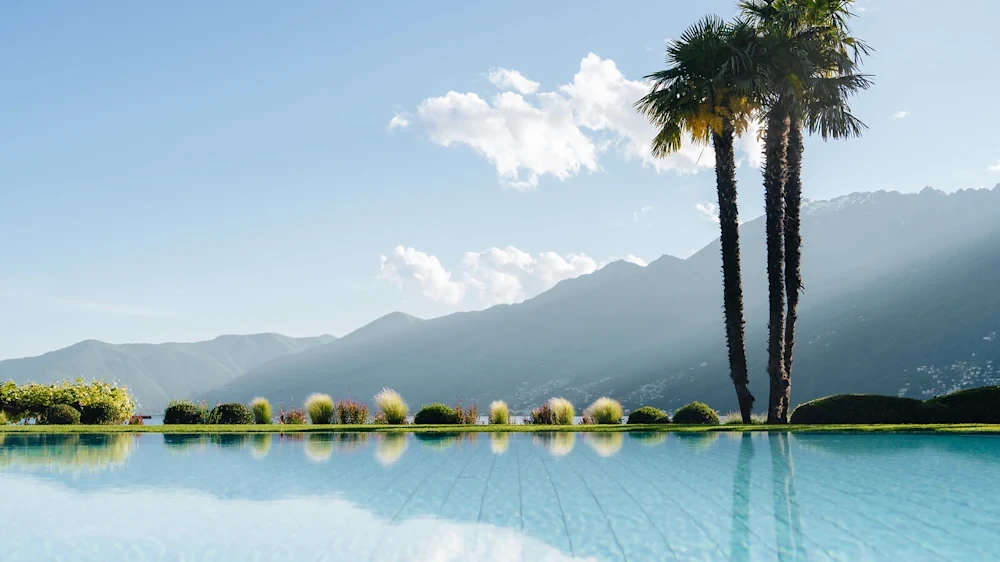 Elegant pool, palm trees and mountain scenery at Hotel Eden Roc Ascona