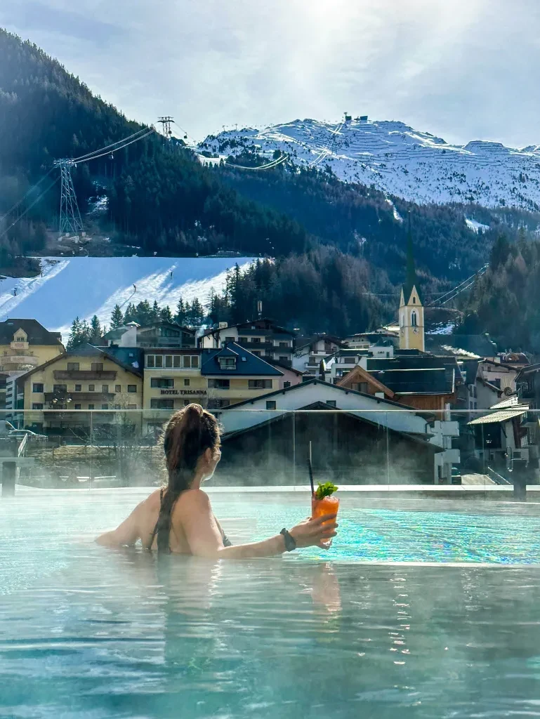 Heated outdoor pool overlooking Ischgl village and snowy mountain infrastructure