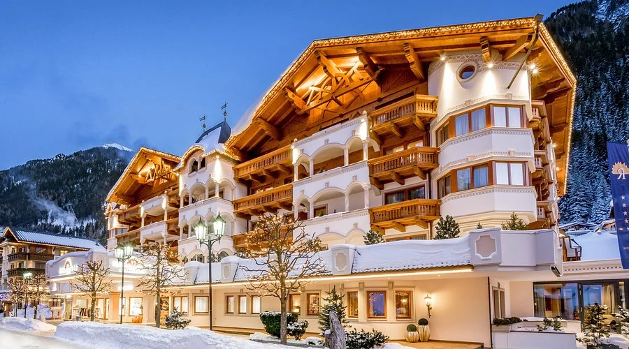 Trofana Royal Ischgl illuminated in winter with its complete Alpine facade and snowy approach